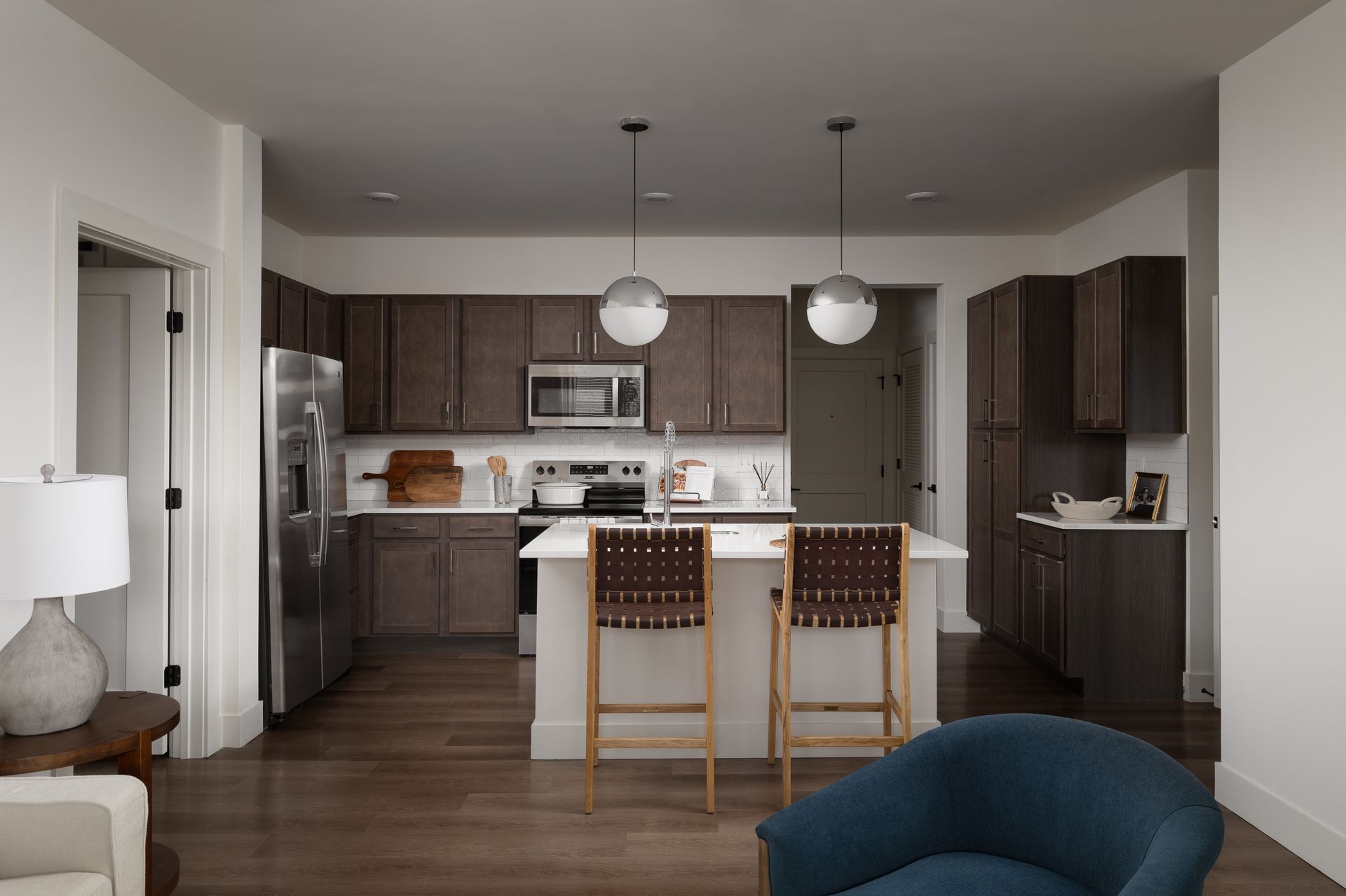 Kitchen with wood cabinets, stainless steel appliances, island with stools, and pendant lights.