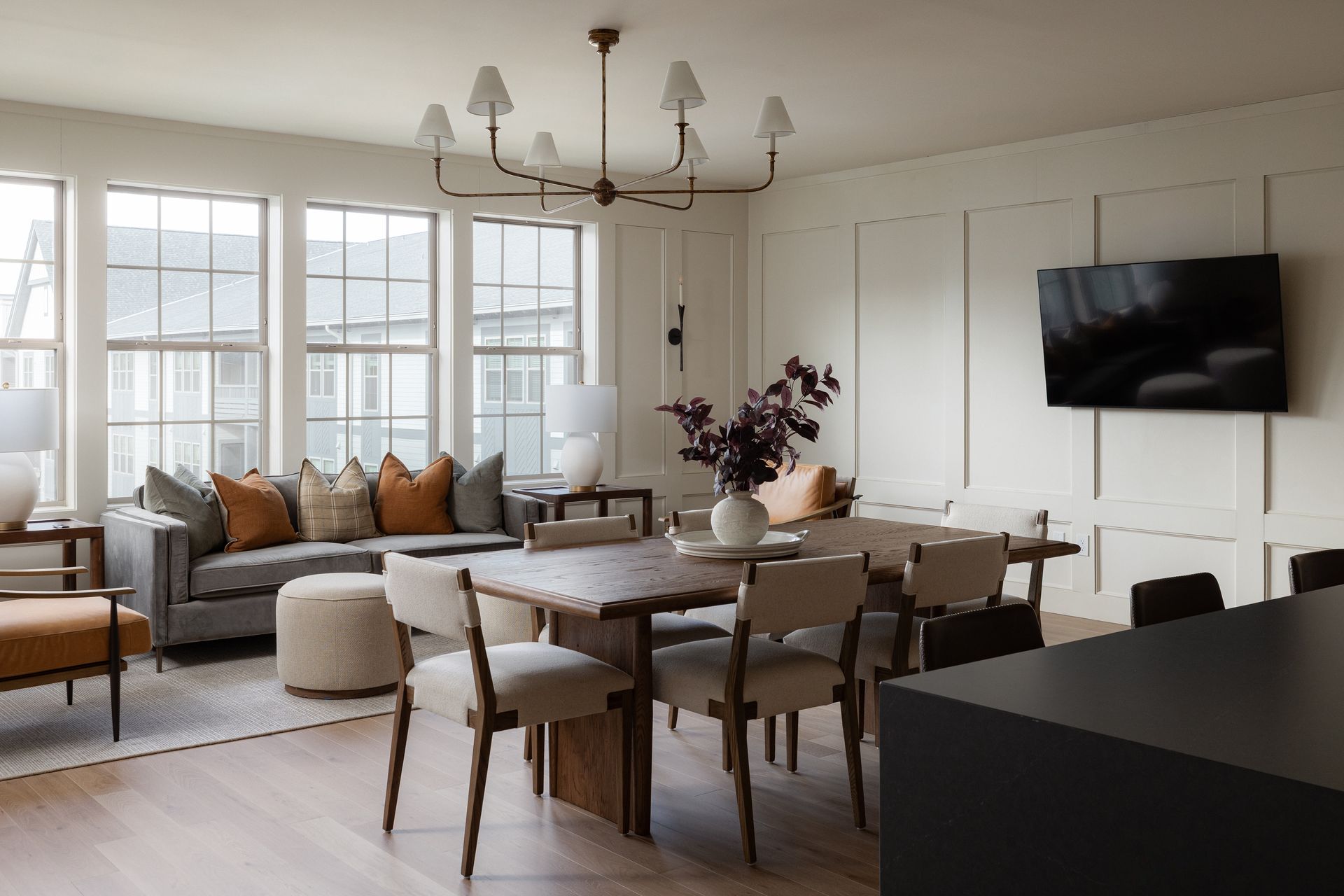 Spacious open-concept living/dining area with light wood floors, large windows, and a dark wood dining table.