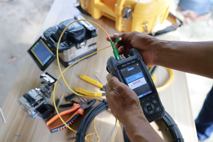 A person is using a device to test a fiber optic cable.