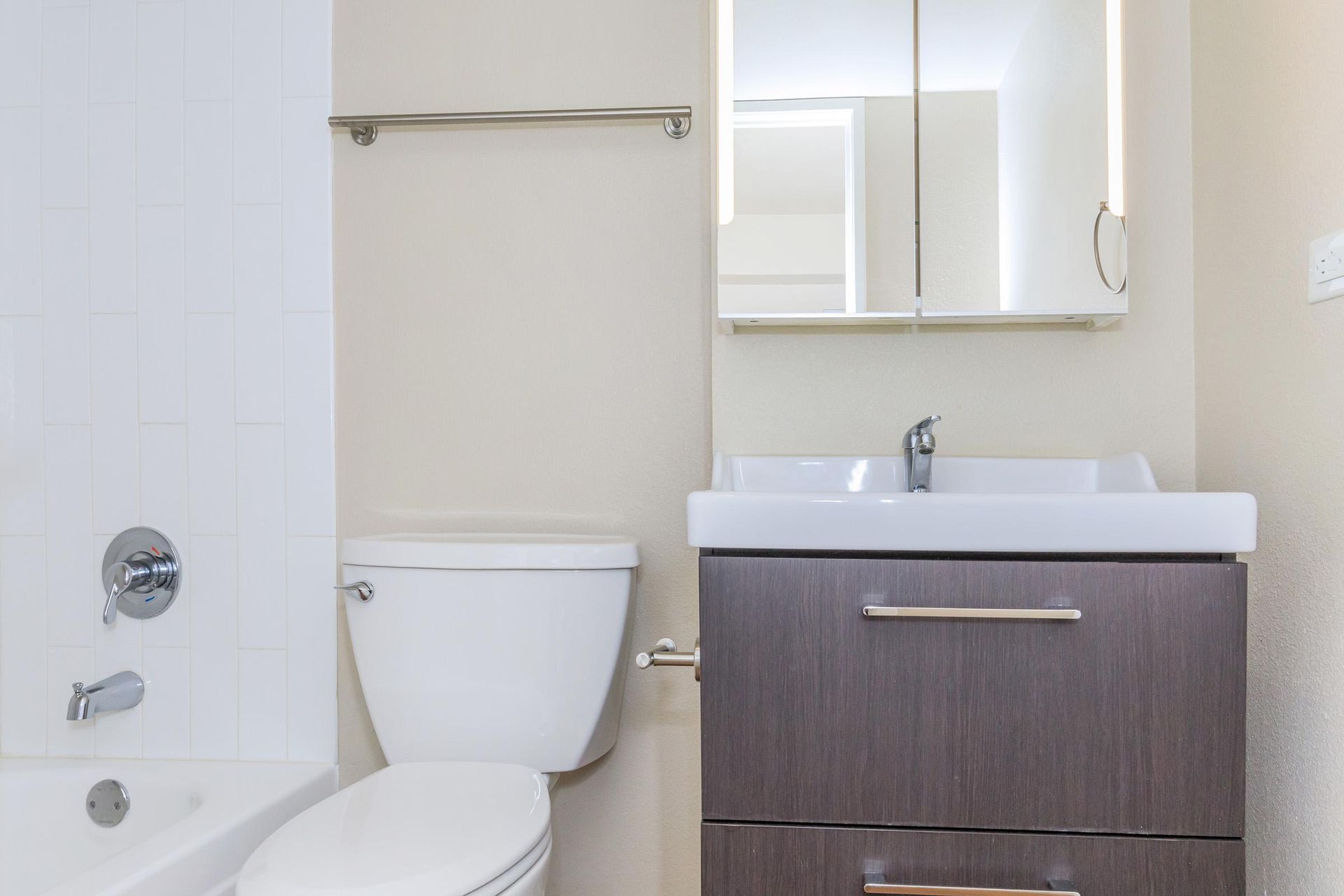 Bathroom with a toilet, sink, medicine cabinet, and tub. White, beige, and gray color scheme.