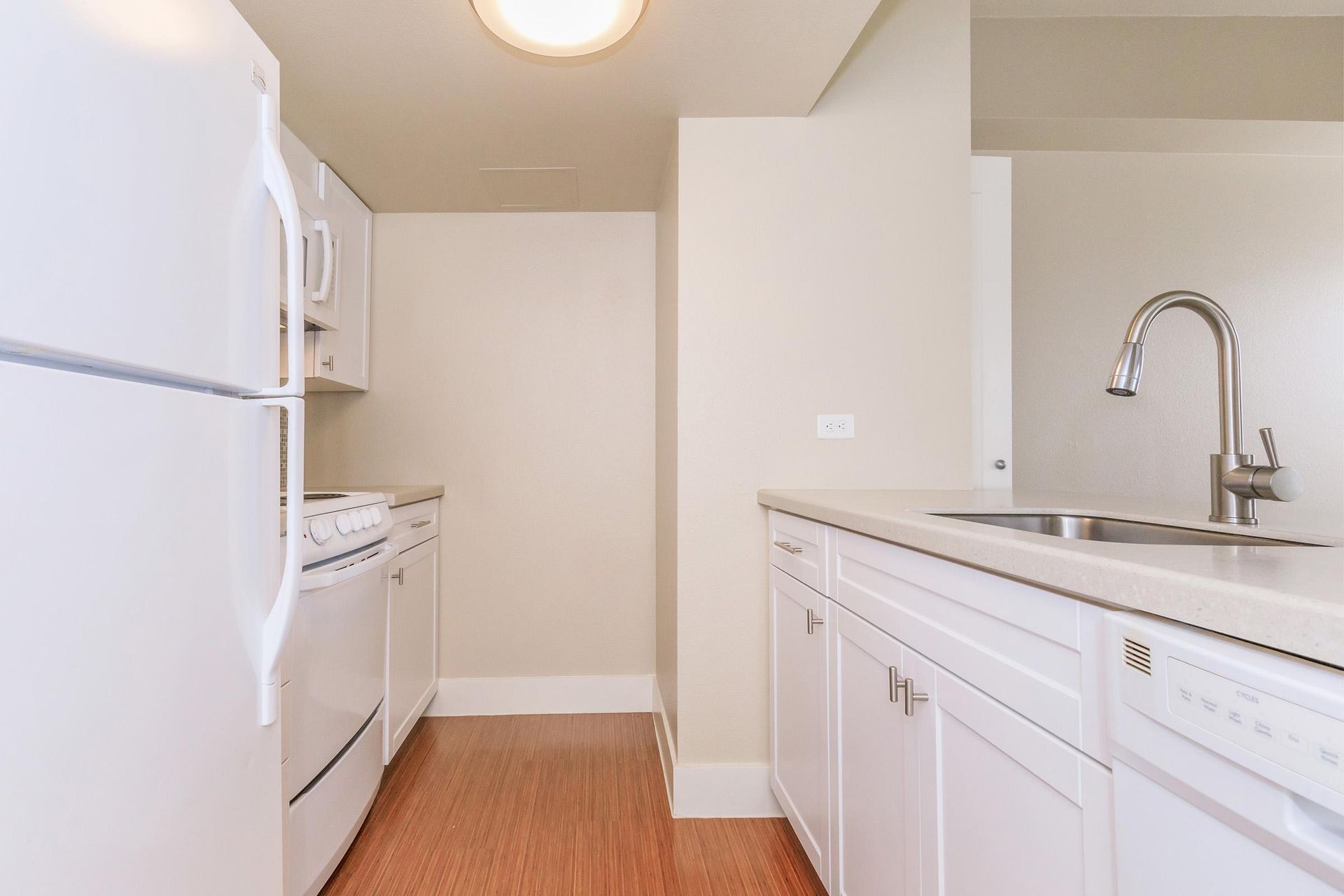 Small white kitchen with a refrigerator, cabinets, and sink.