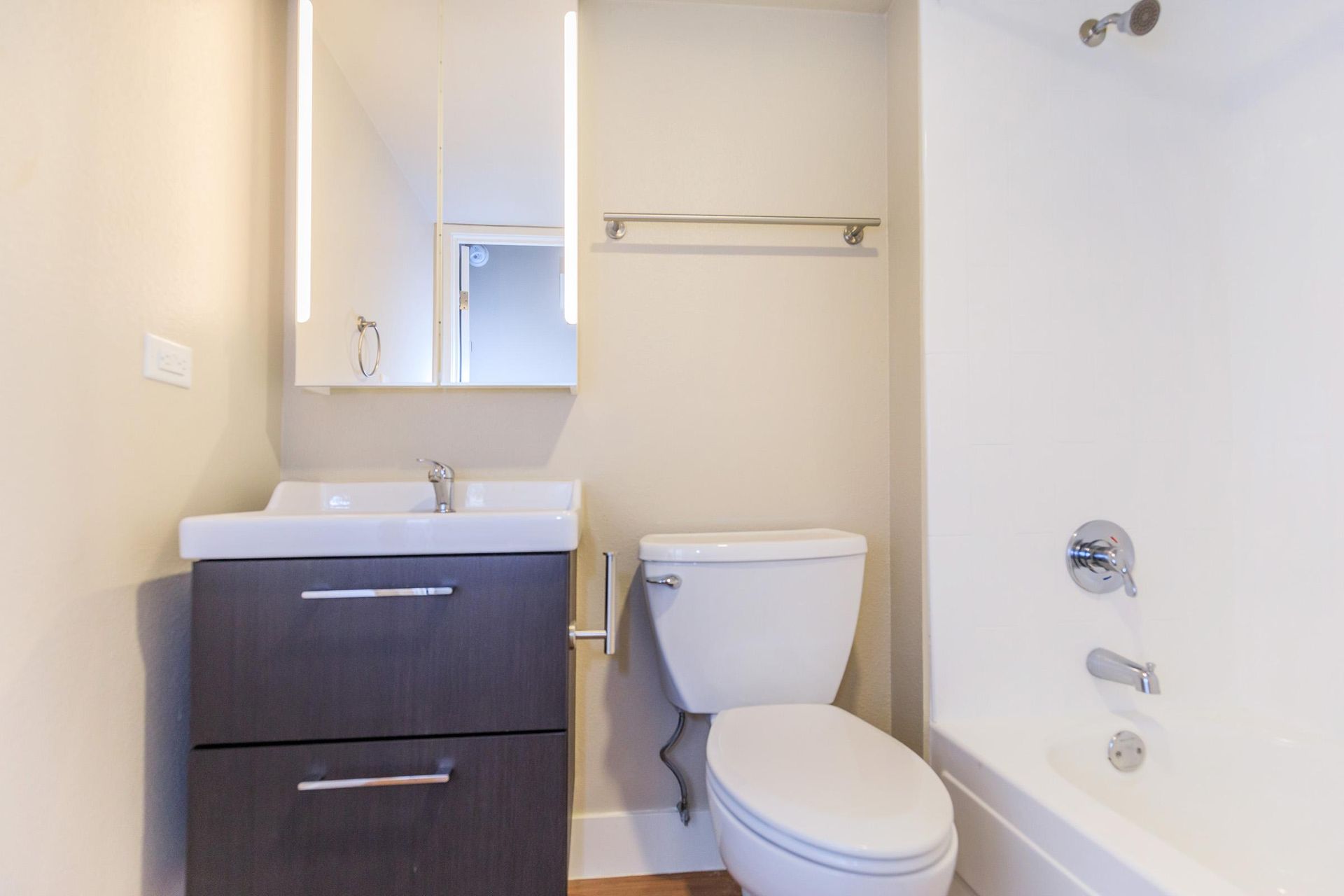 Bathroom with white fixtures, dark gray vanity, and neutral walls.