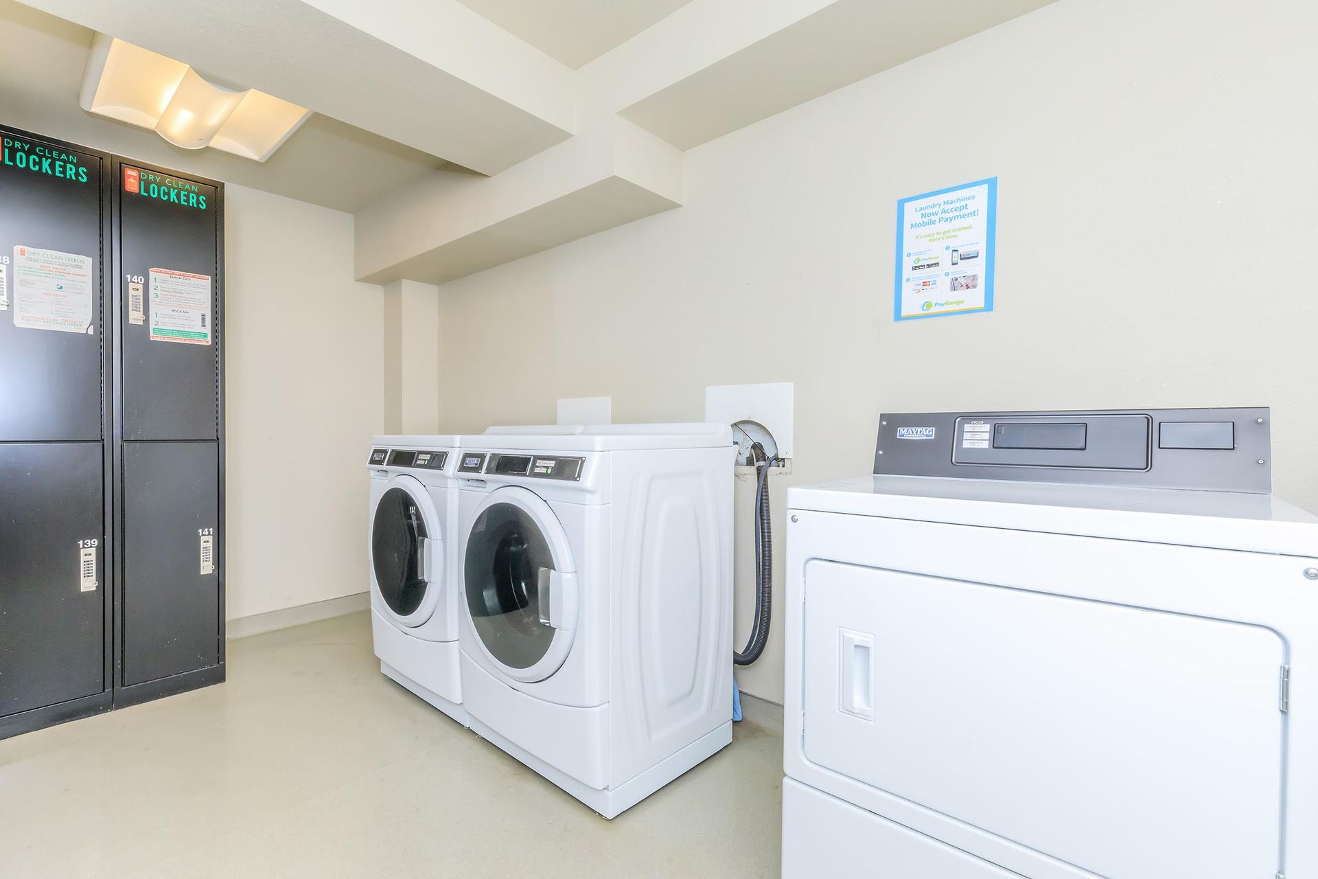 Laundry room with two washers, a dryer, lockers, and a wall sign.