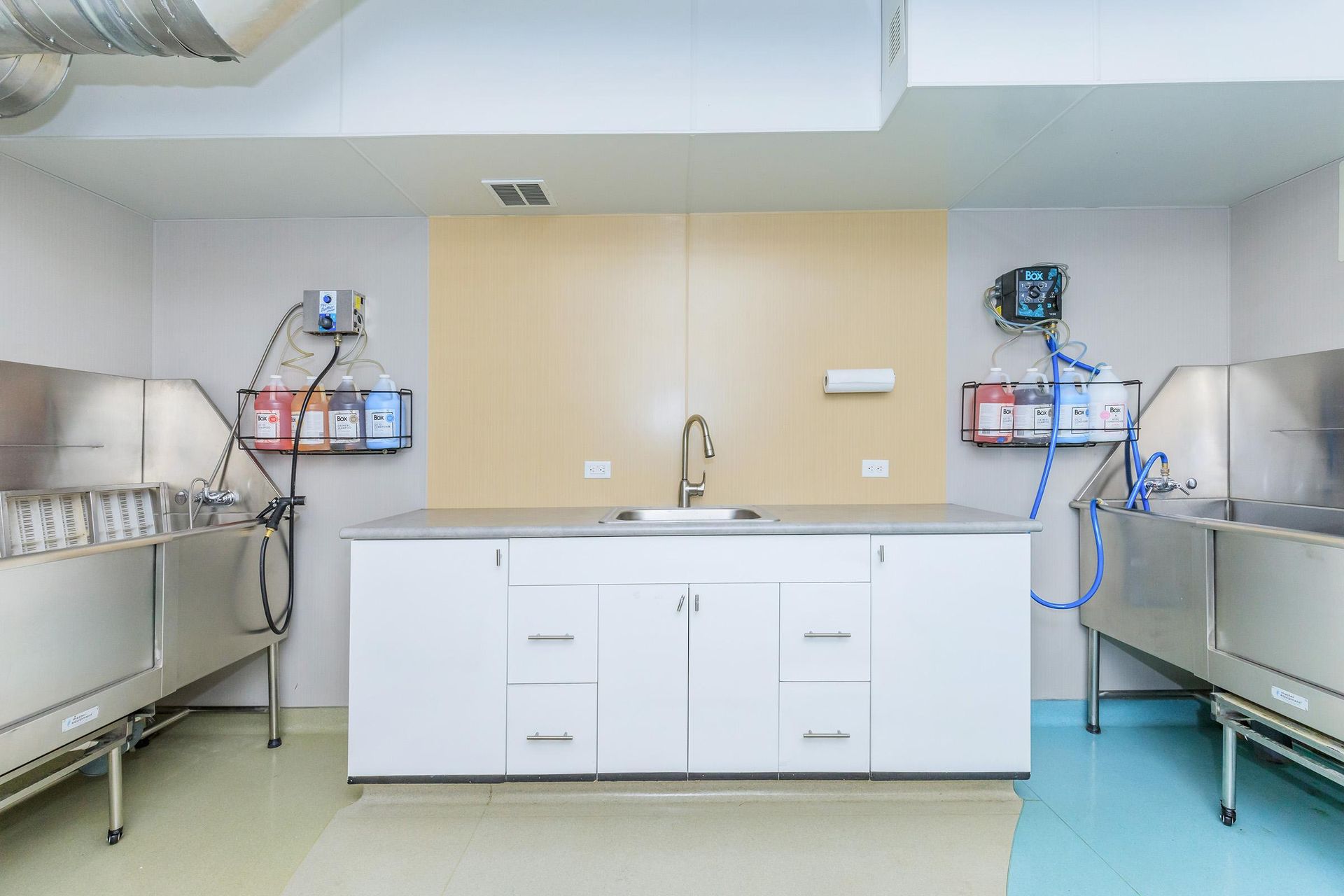 A dog grooming station with two stainless steel tubs and a central countertop with a sink.