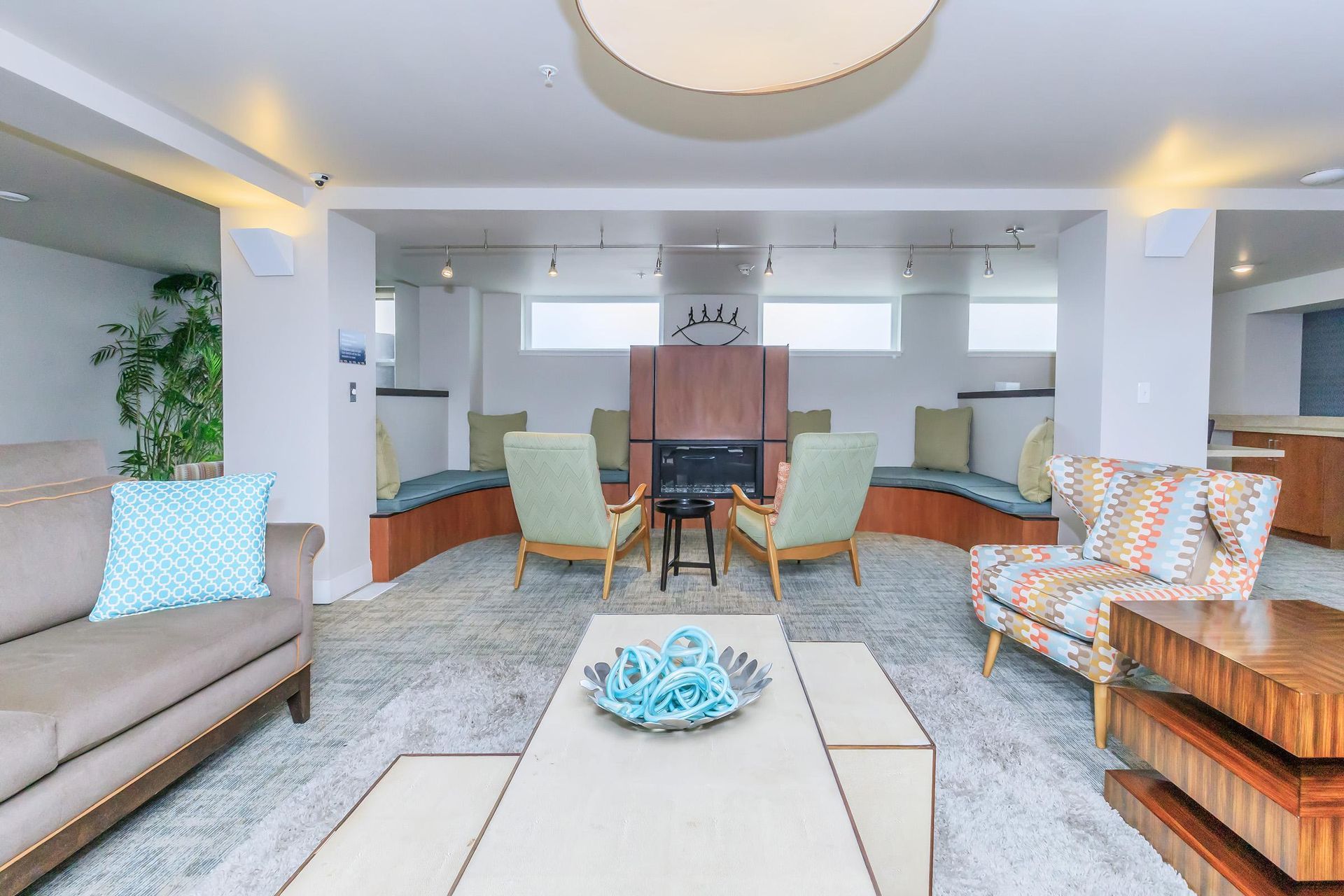 Lounge area with fireplace, seating, and a coffee table on a large rug.