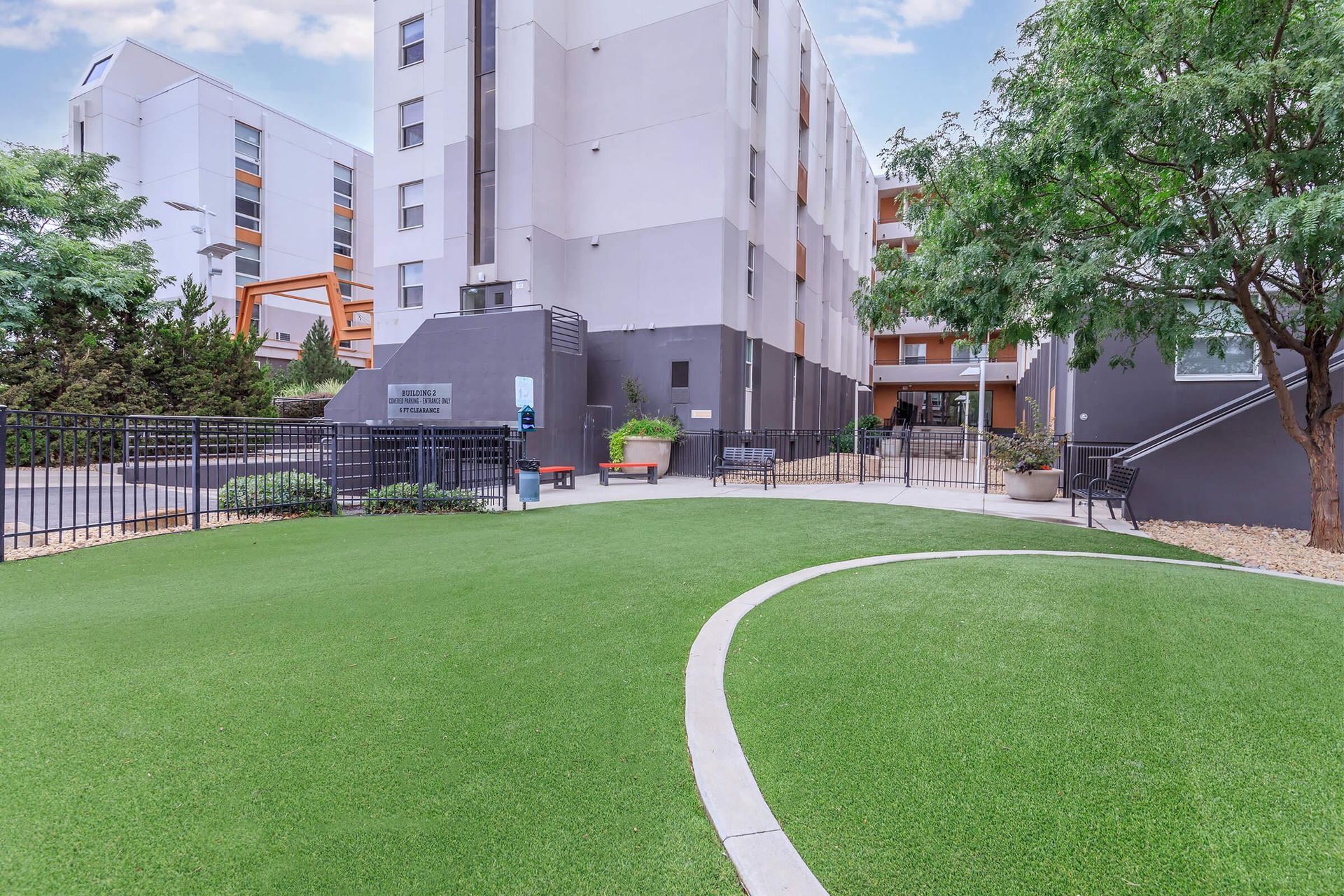 Green lawn with a curving path in front of a modern apartment building.