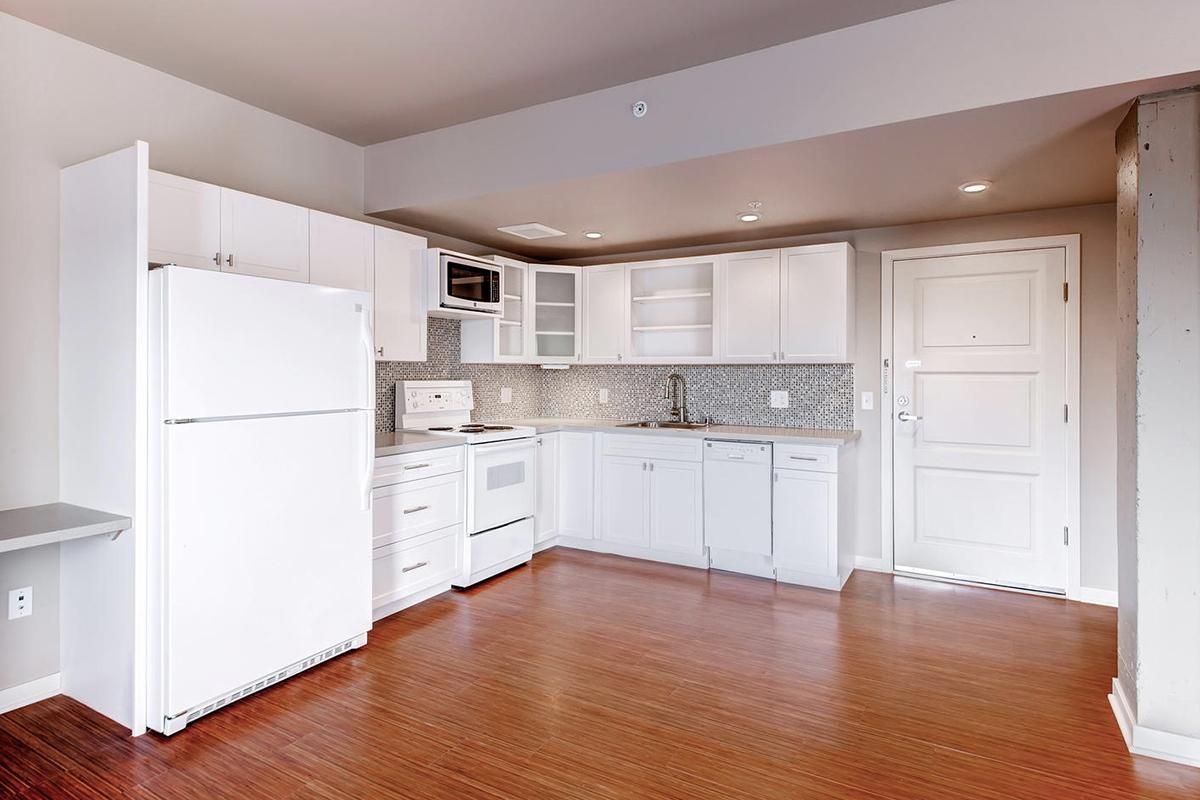 White kitchen with appliances, cabinets, and hardwood floors.