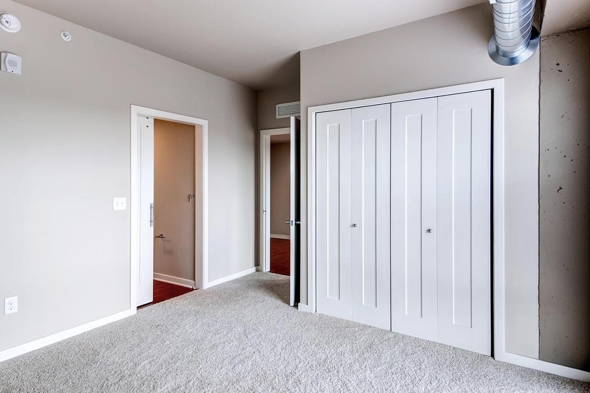 Bedroom with closed white closet doors, doorway, and light gray carpet.