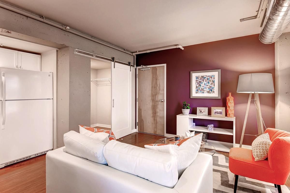 Living room: white sofa, orange chair, and artwork against a plum wall.