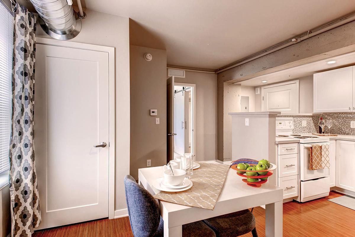 Kitchen and dining area with white table, gray walls, and white appliances.