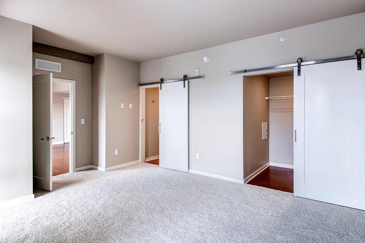 Bedroom interior with light gray walls, carpet, two white sliding barn doors, and doorway.