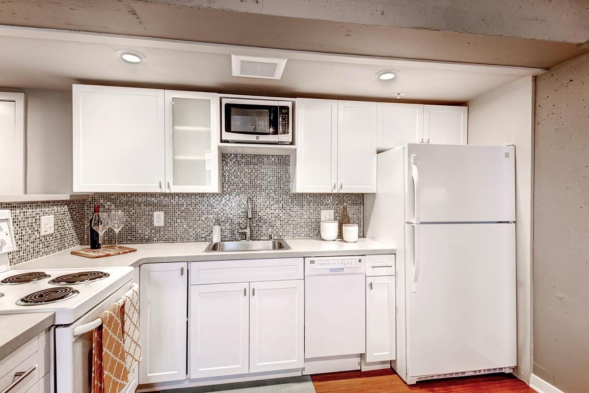 White kitchen with appliances, cabinets, and a microwave above the sink.