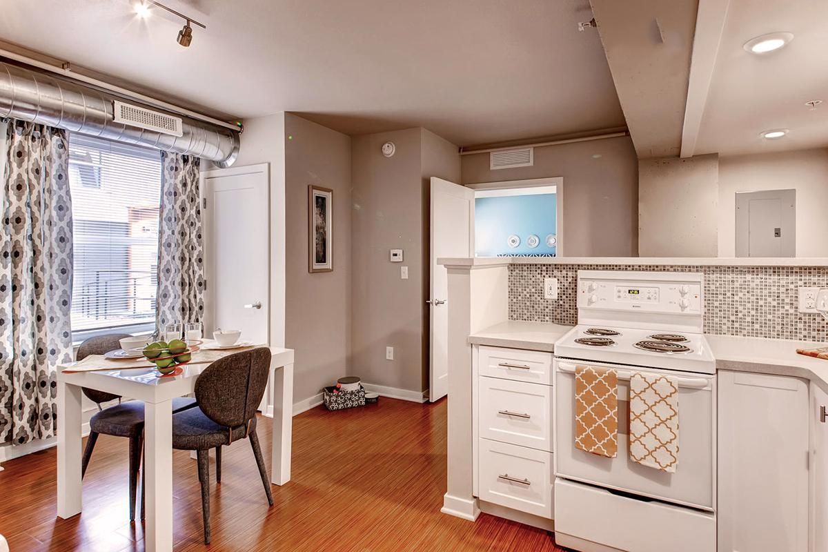 Small, open-concept apartment with a white kitchen, dining area, and hardwood floors.