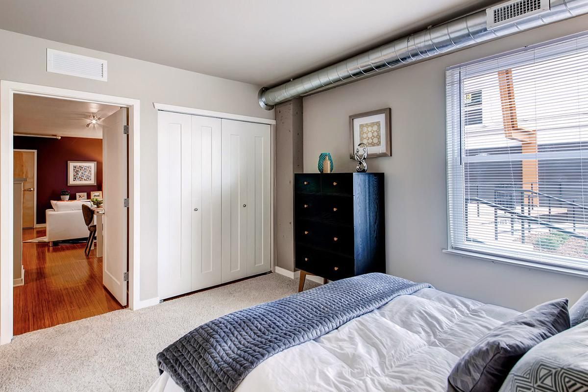 Bedroom with a bed, dresser, closet, and open doorway leading to a dining area.