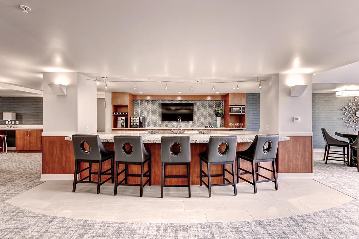 Bar area with granite counter, stools, cabinetry, and a TV.