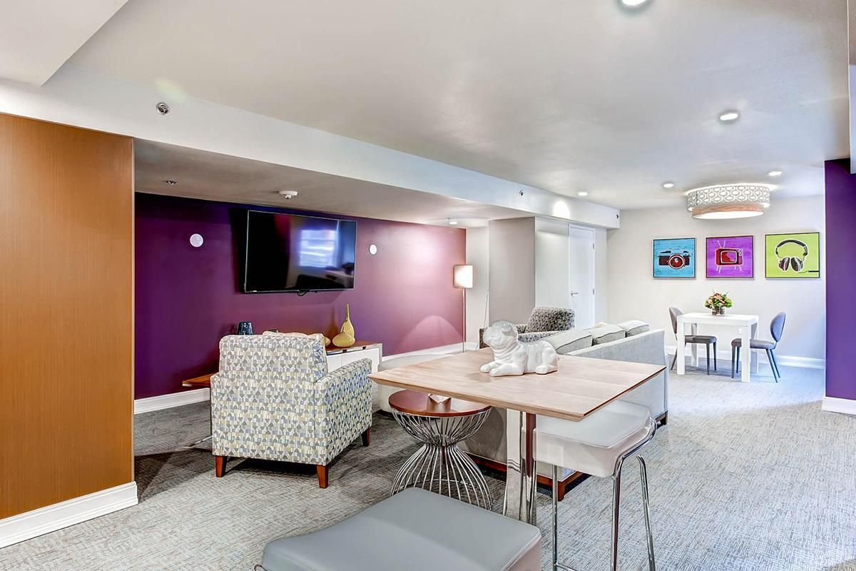 Living room with purple accent walls, TV, patterned chair, and small dining area.