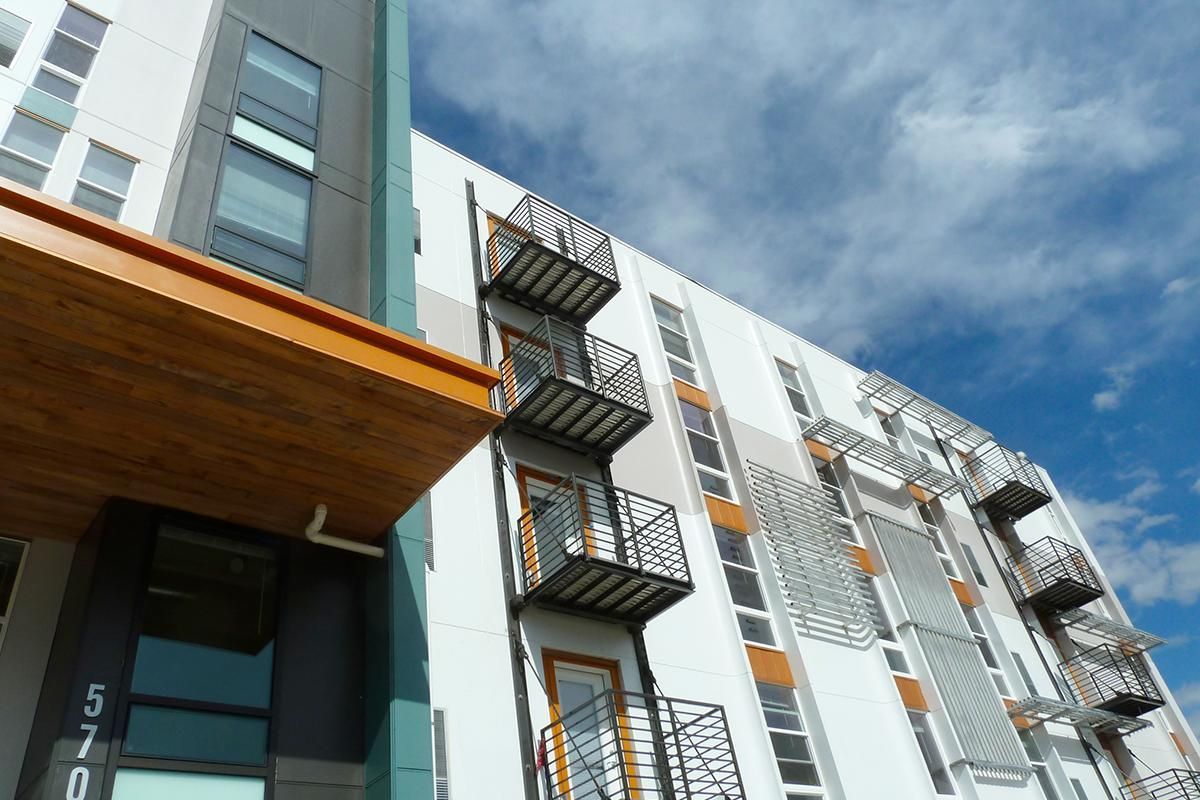 Modern apartment building with exterior staircases against a cloudy blue sky.