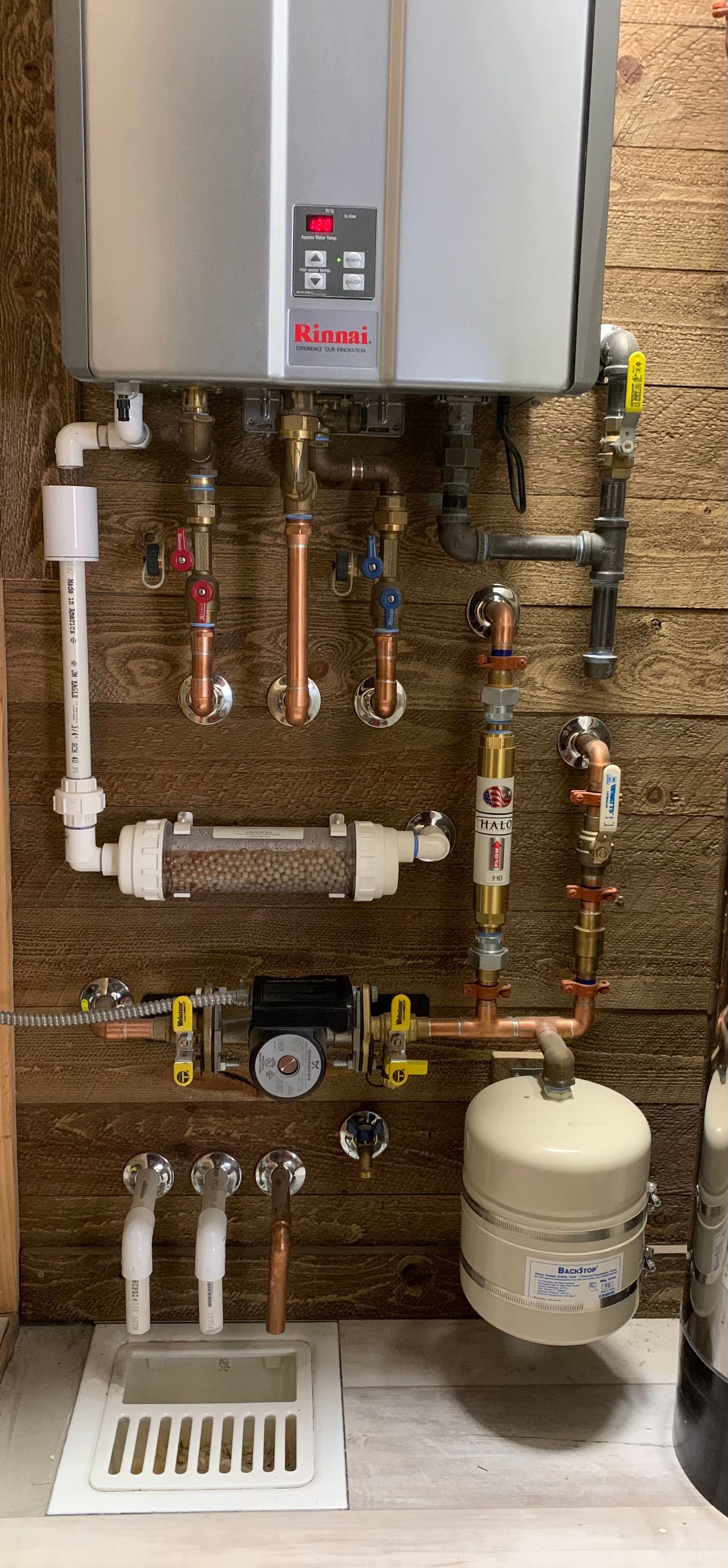 Rightway Plumbing Sewer And Drain - A water heater is sitting on a wall next to a bunch of pipes.