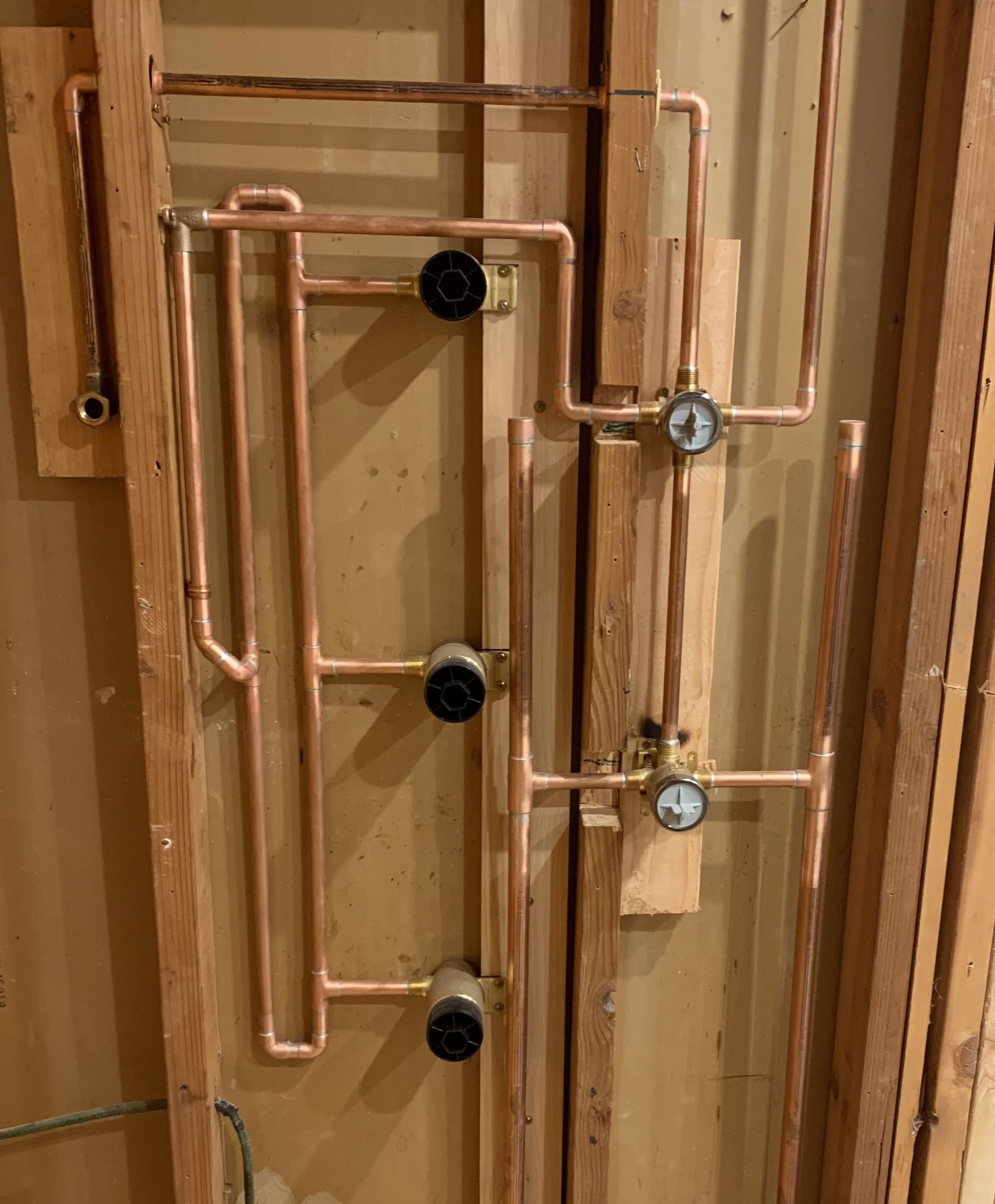 Rightway Plumbing Sewer And Drain - A bunch of copper pipes are hanging on a wooden wall.