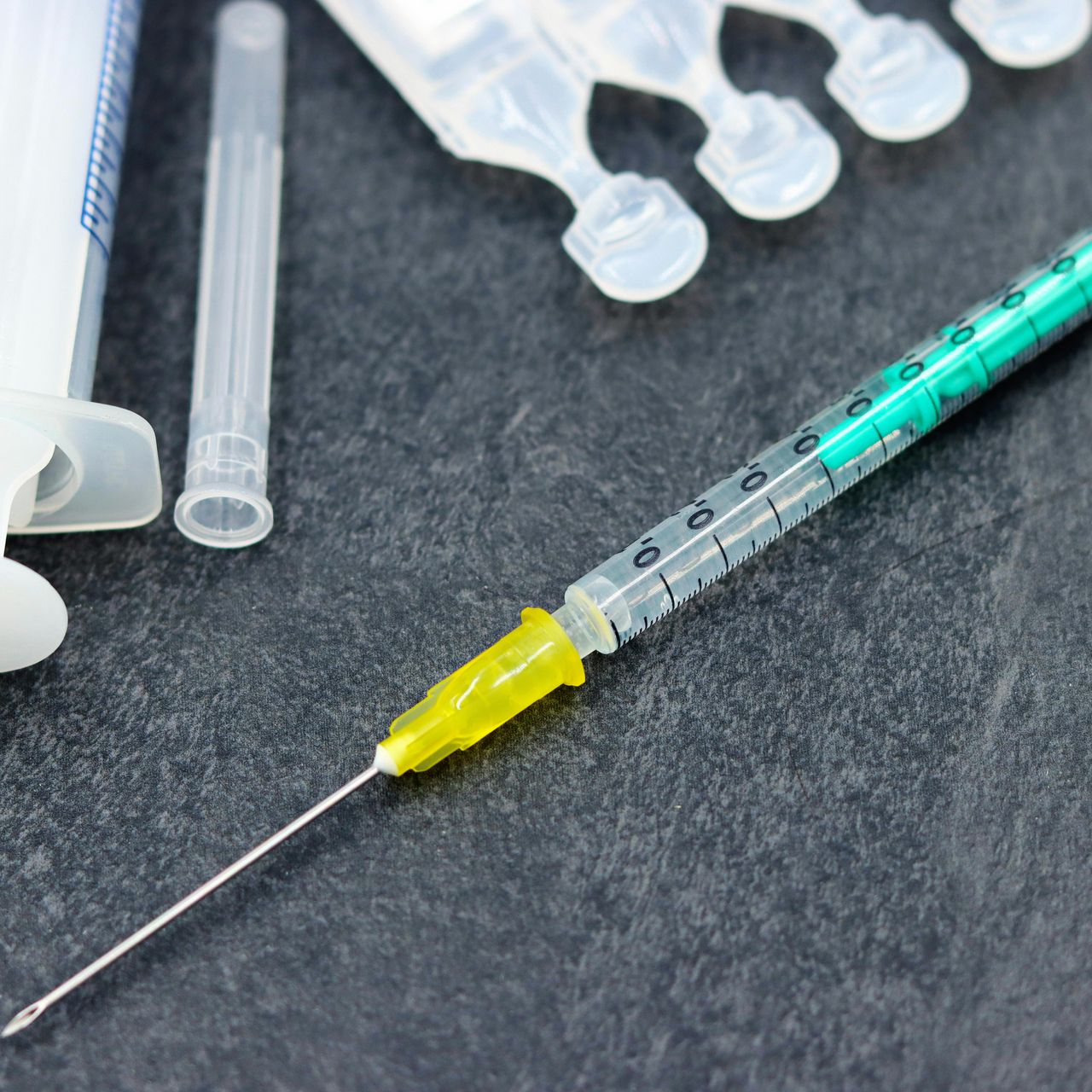 Pile of discarded trash and furniture on a street; includes black bags, cardboard, and a red cart.