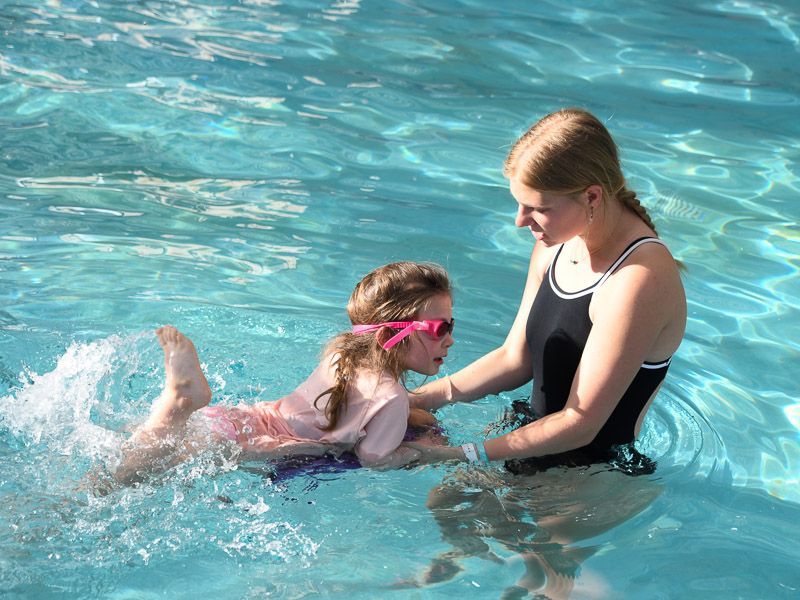 Children in pool learning to swim with instructor