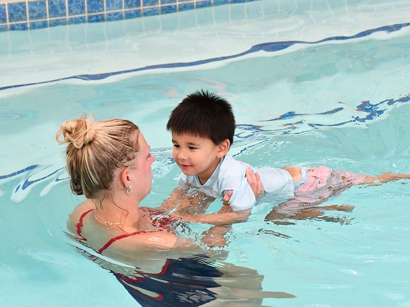 Children in pool learning to swim with instructor