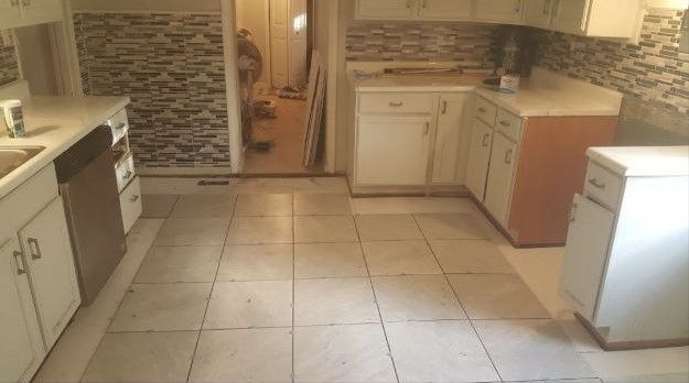 A kitchen with white cabinets , a sink , and a dishwasher.