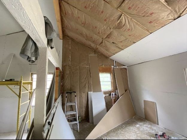 A room with a ladder and a lot of pieces of cardboard on the floor.