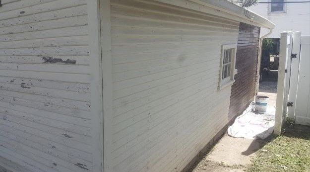 A white house is being painted in a backyard.