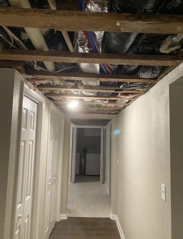 A hallway in a house with a wooden ceiling and a few doors.