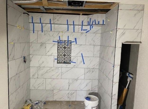 A bathroom under construction with blue tape on the wall.