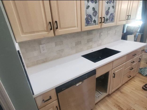 A kitchen with white counter tops and wooden cabinets