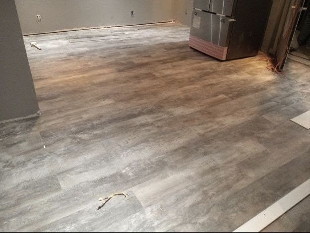 A kitchen with a wooden floor and a refrigerator.