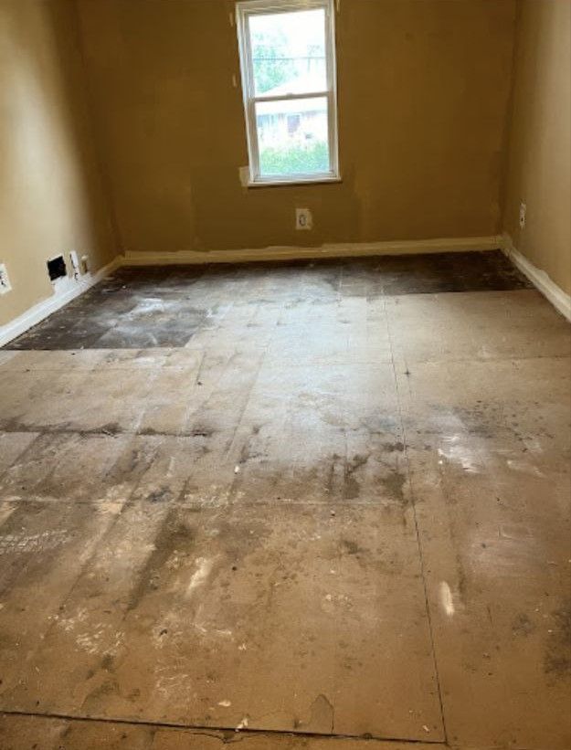 A room with a dirty floor and a window.