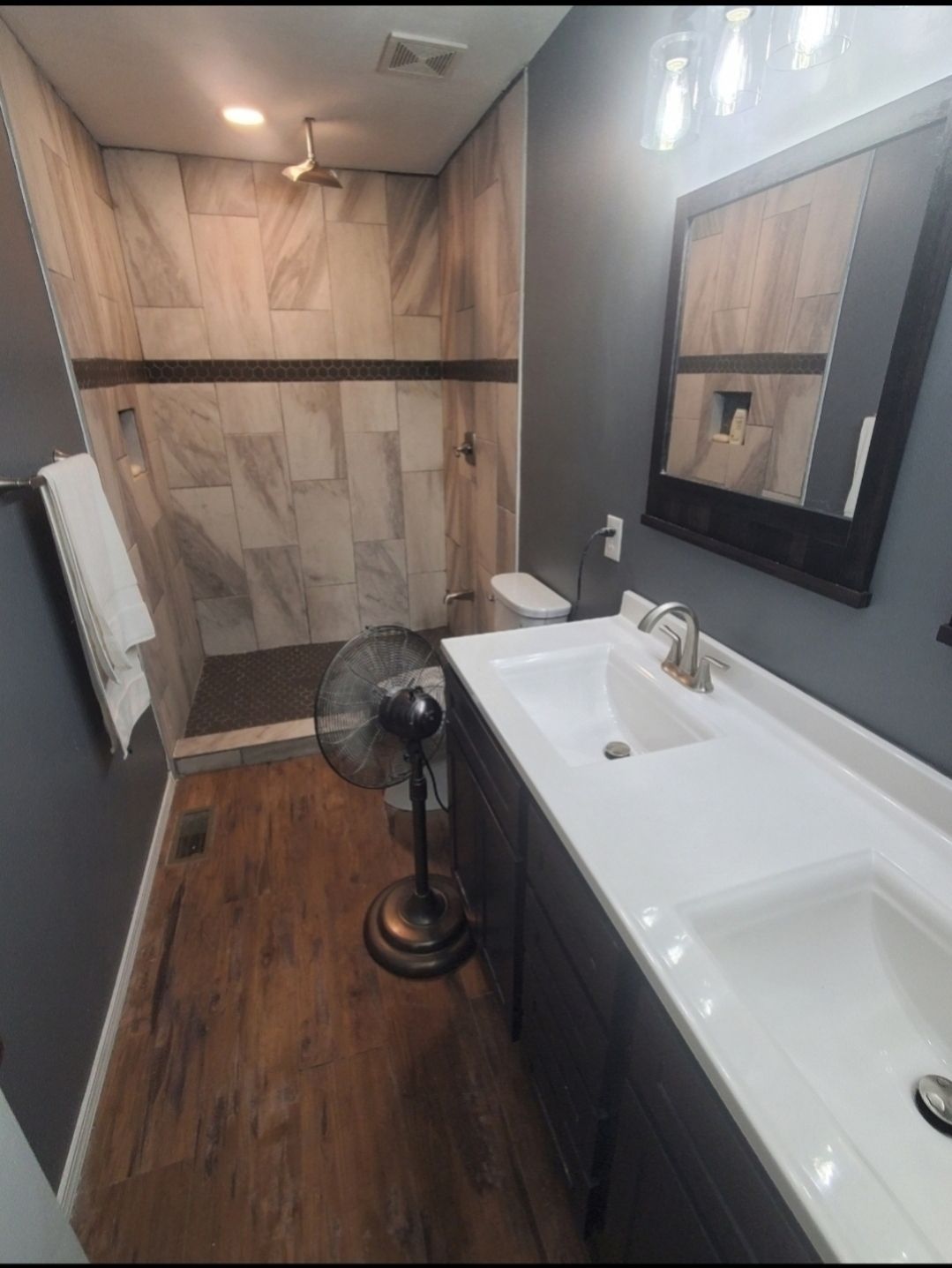 A bathroom with a sink a mirror and a fan