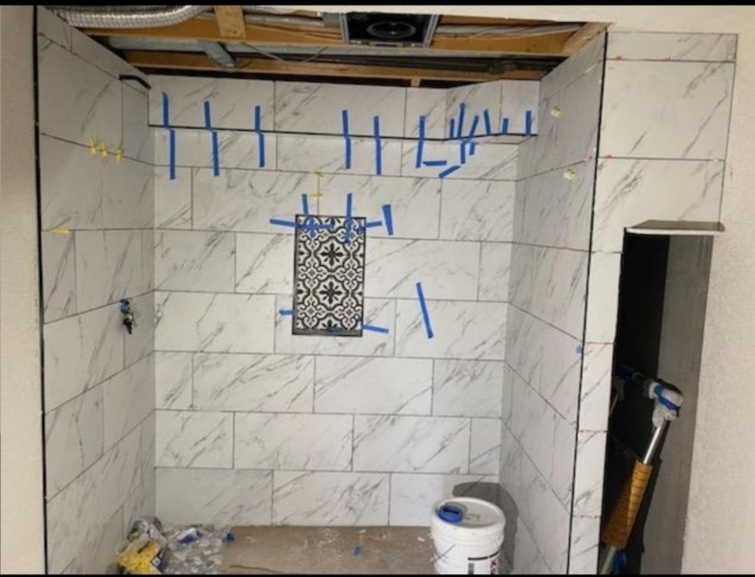 A bathroom with white tiles and blue tape on the wall