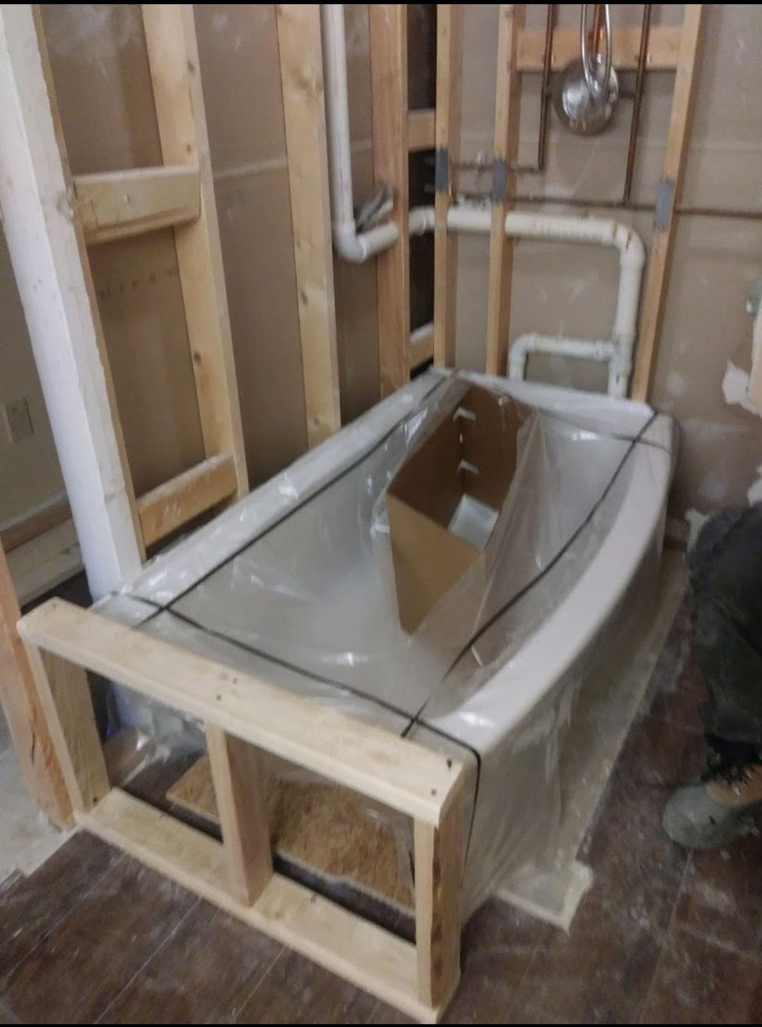 A bathtub is wrapped in plastic and sitting on a wooden frame
