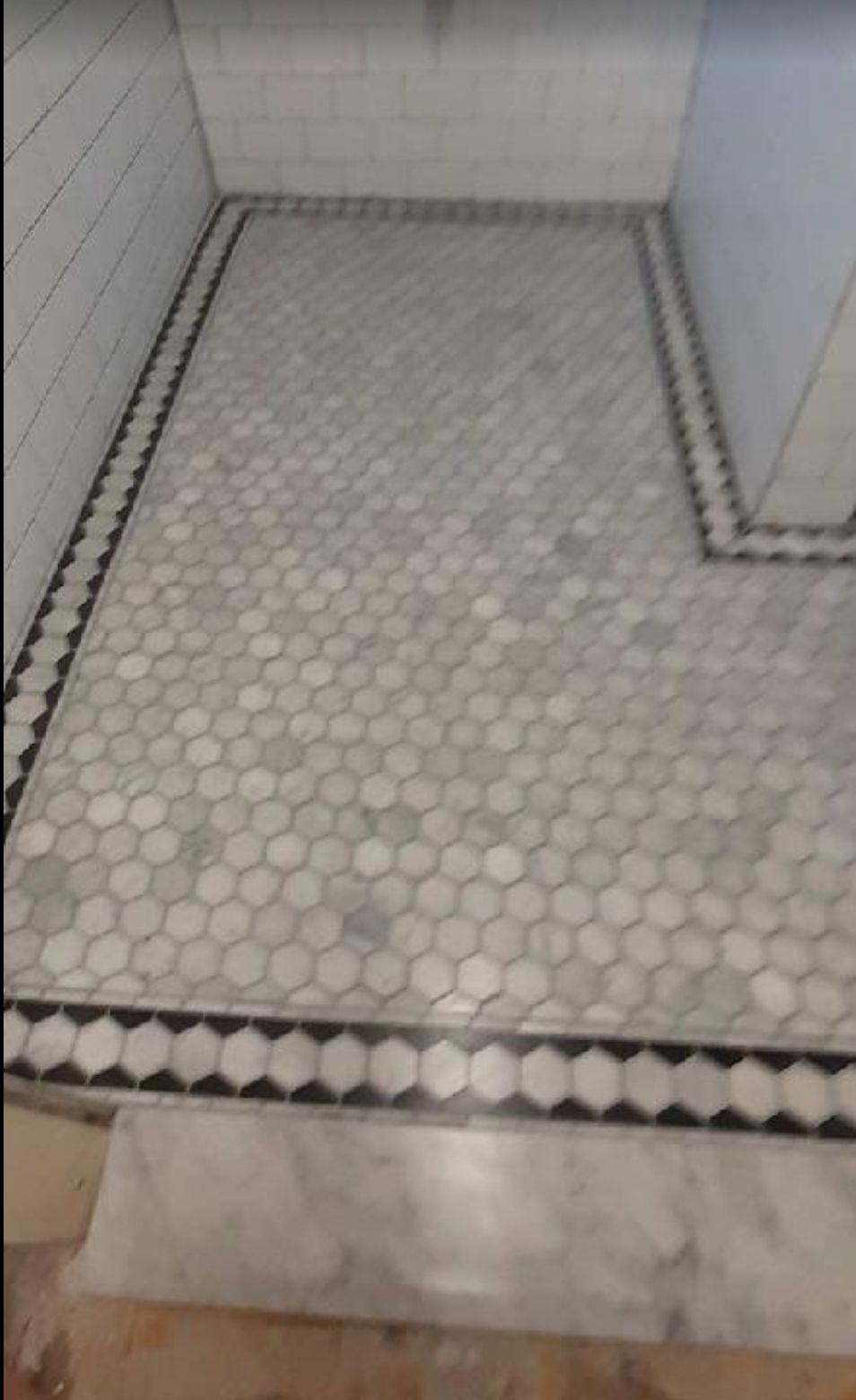 A tiled floor in a bathroom with a black and white border.