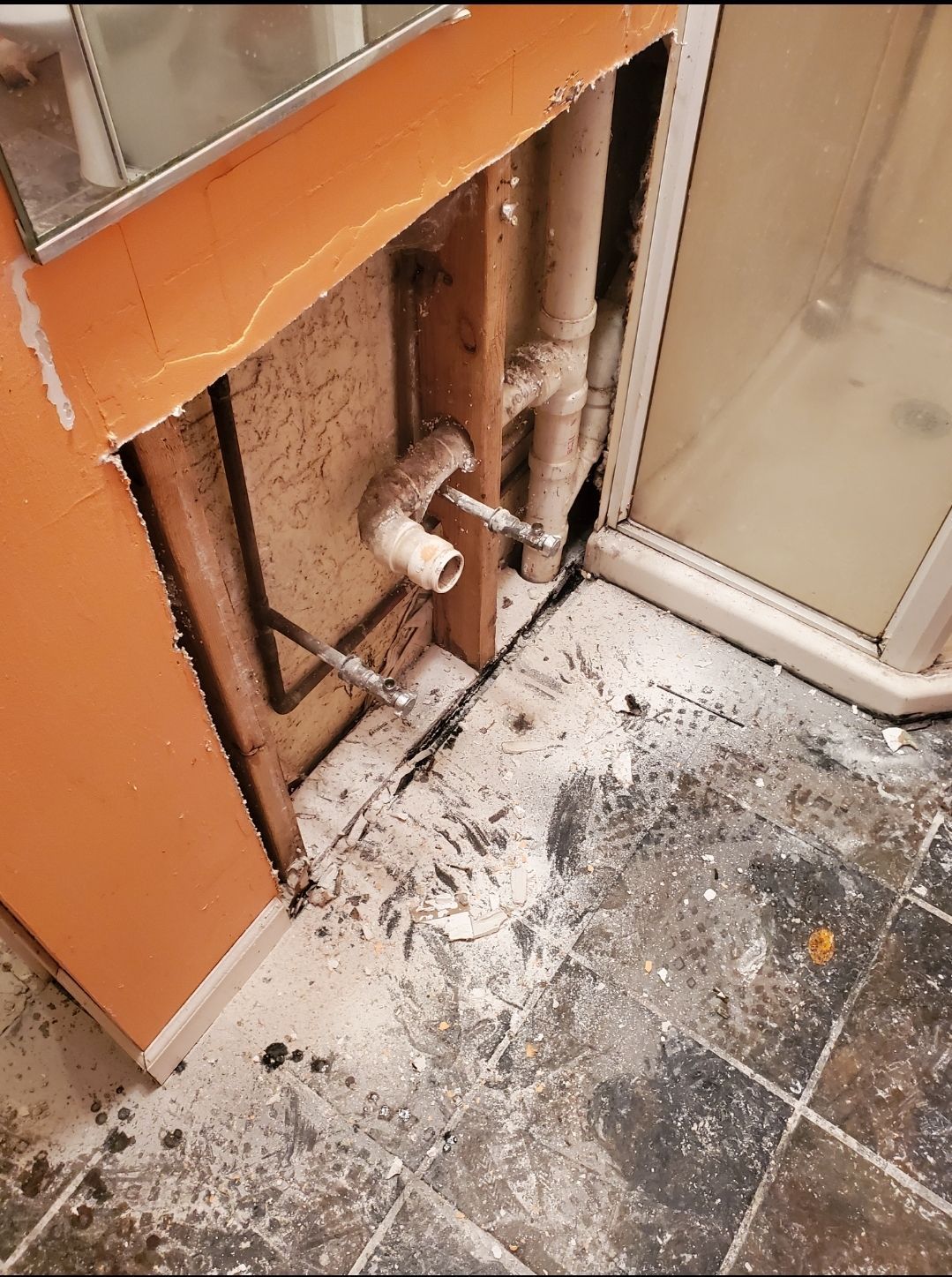 A bathroom with a broken sink and a shower stall.