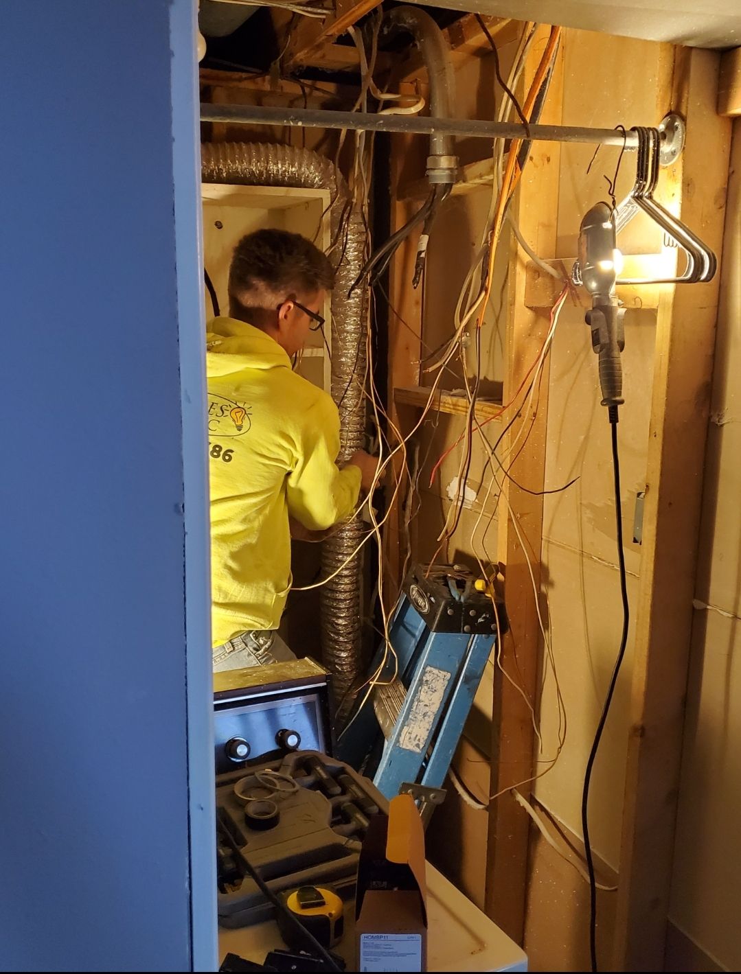 A man in a yellow shirt is working on a heater