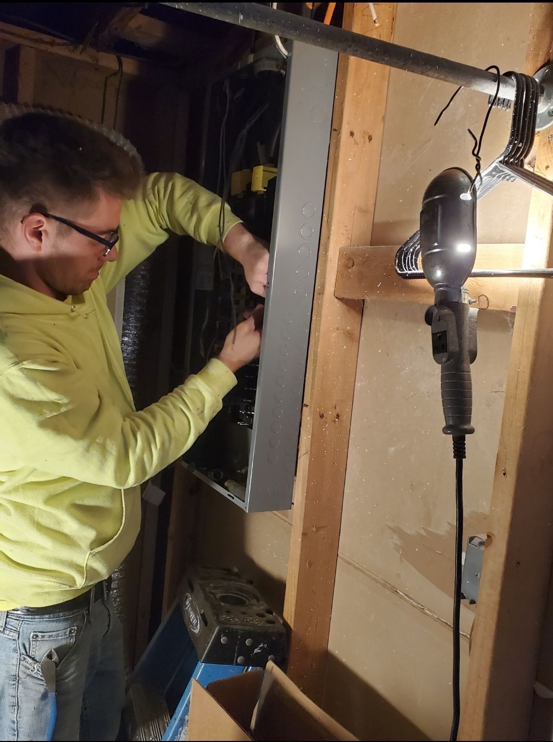 A man in a yellow shirt is working on an electrical box