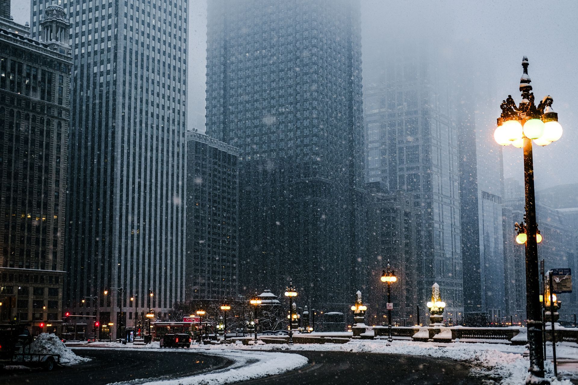 Snowy Chicago cityscape with skyscrapers, streetlights, and snow-covered roads.