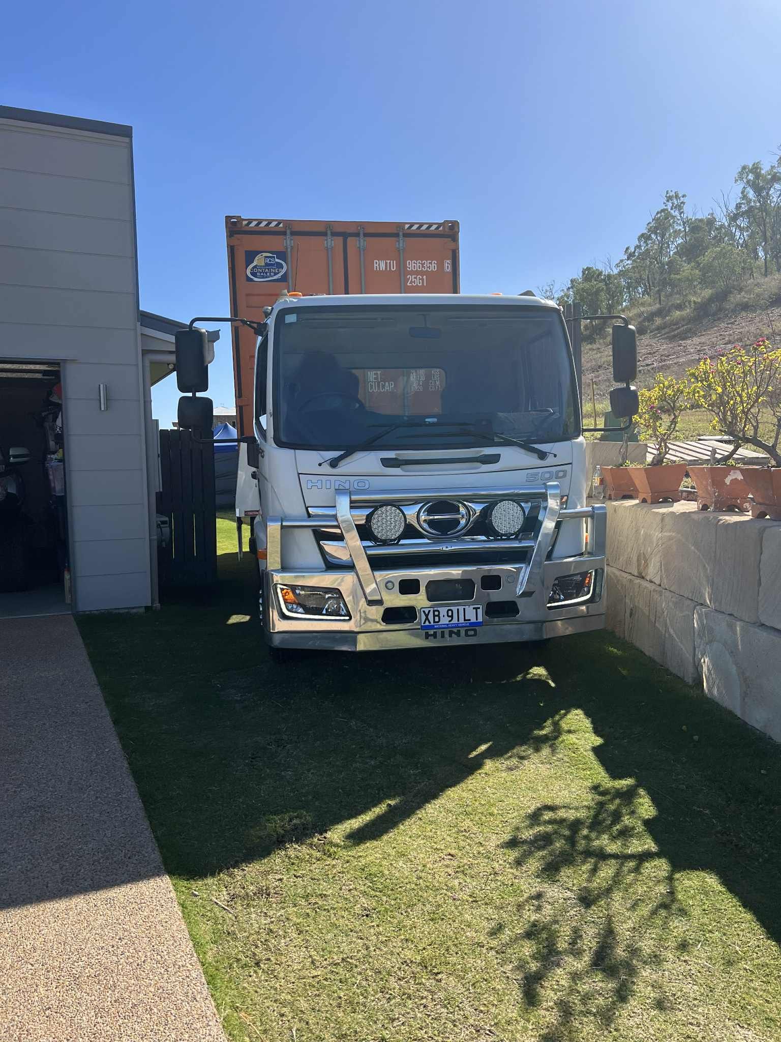 White Truck With Orange Shipping Container Parked on Grass Next to a Building  — Rockhampton Container Sales in Kawana, QLD