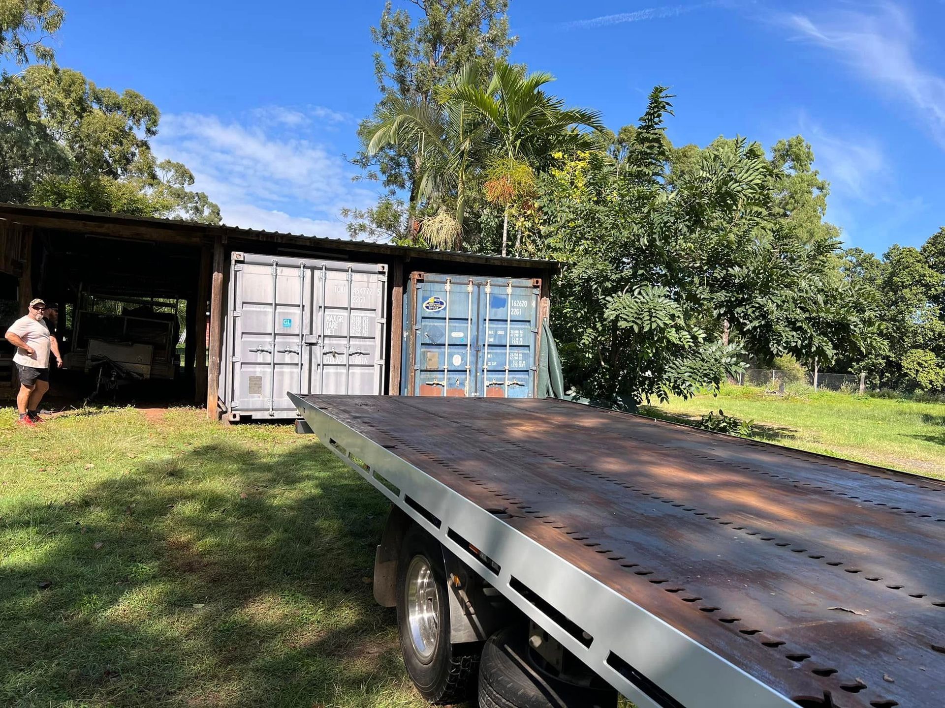 Flatbed Truck Bed in Foreground, Two Cargo Containers Under a Shelter  — Rockhampton Container Sales in Kawana, QLD