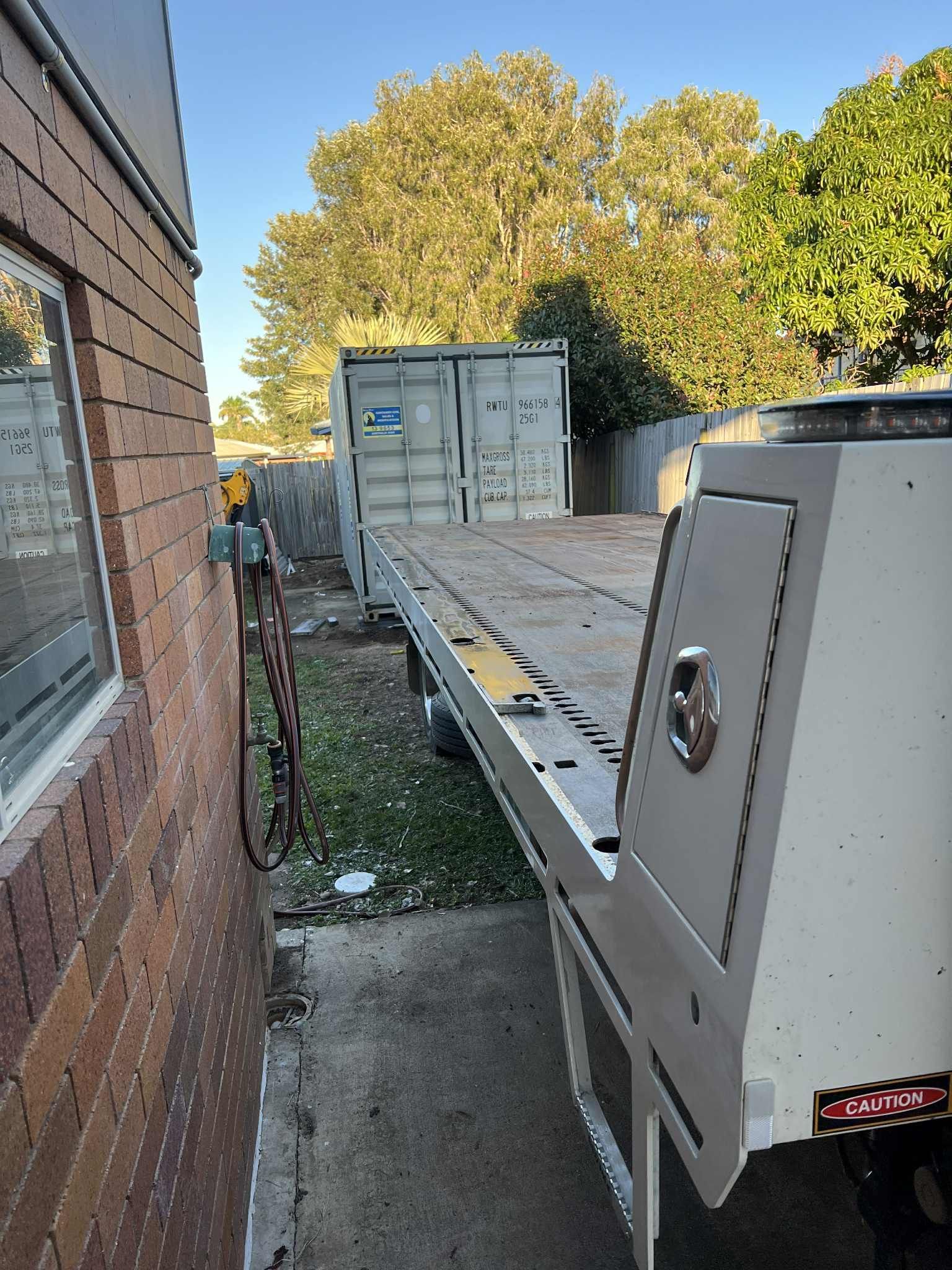 Flatbed Truck Parked Next to a Brick Wall and Shipping Container  — Rockhampton Container Sales in Kawana, QLD