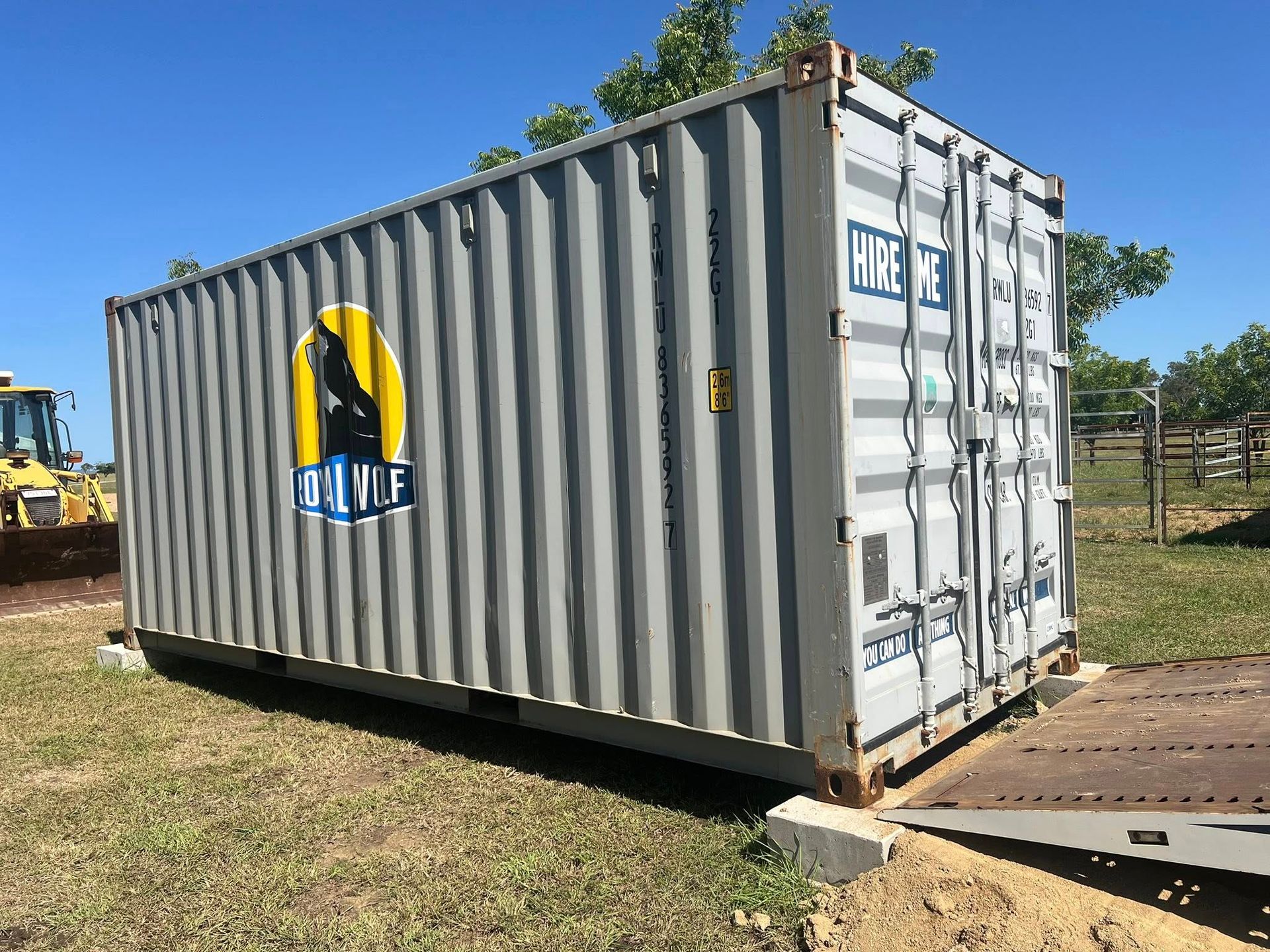 Gray Shipping Container With a Company Logo in a Grassy Field — Rockhampton Container Sales in Kawana, QLD