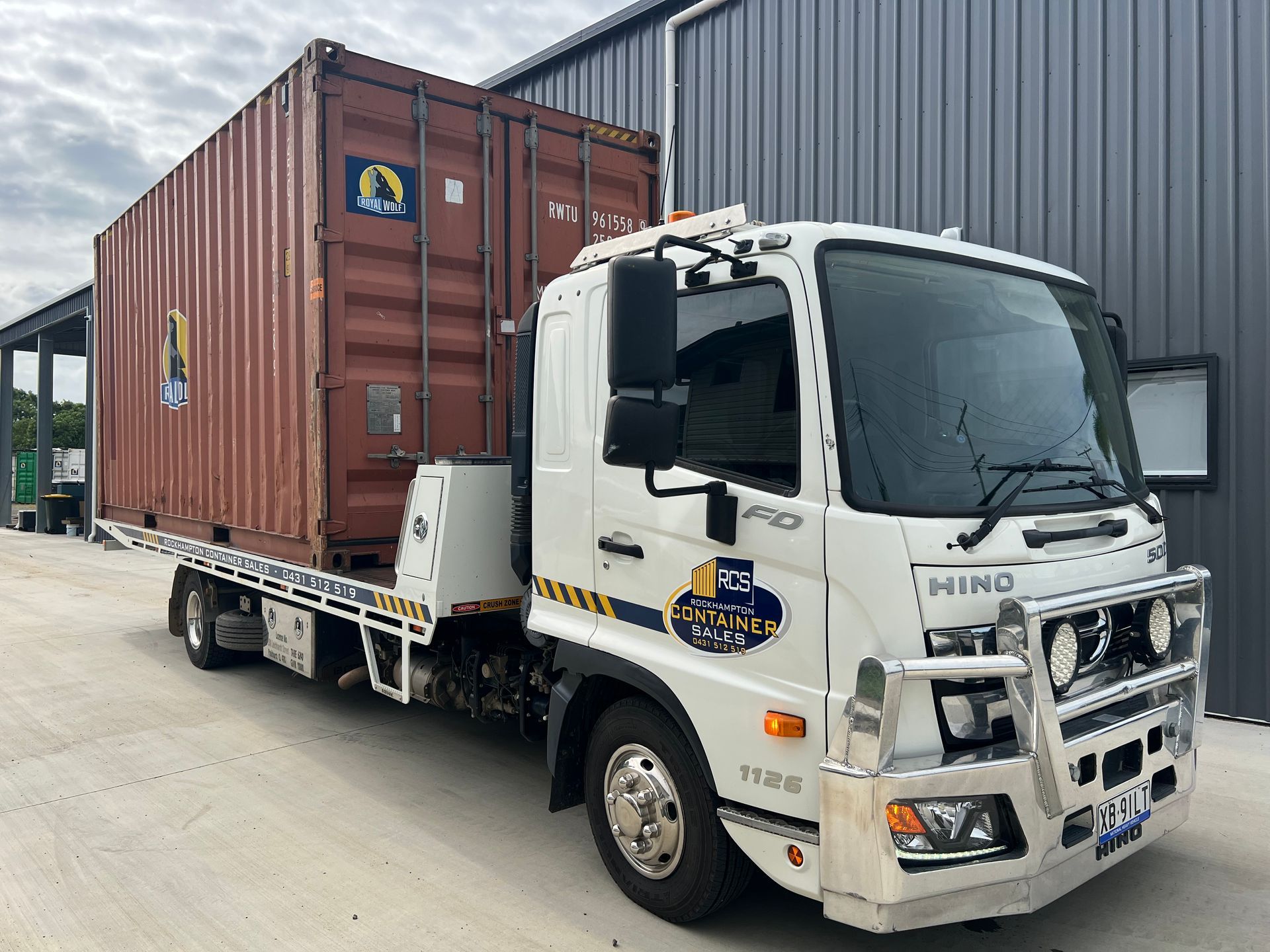 Shipping Container on a Flatbed Truck on Grassy Ground, Blue Sky  — Rockhampton Container Sales in Kawana, QLD