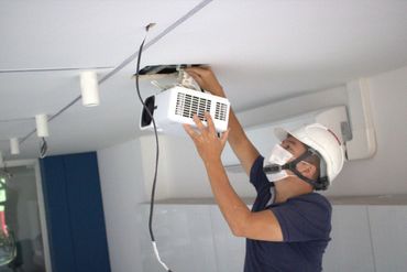 Un hombre con una bata de laboratorio está trabajando en un dispositivo electrónico.