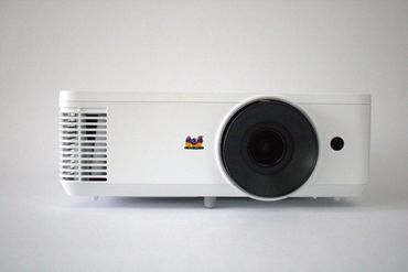 Un proyector negro está sobre una superficie blanca.