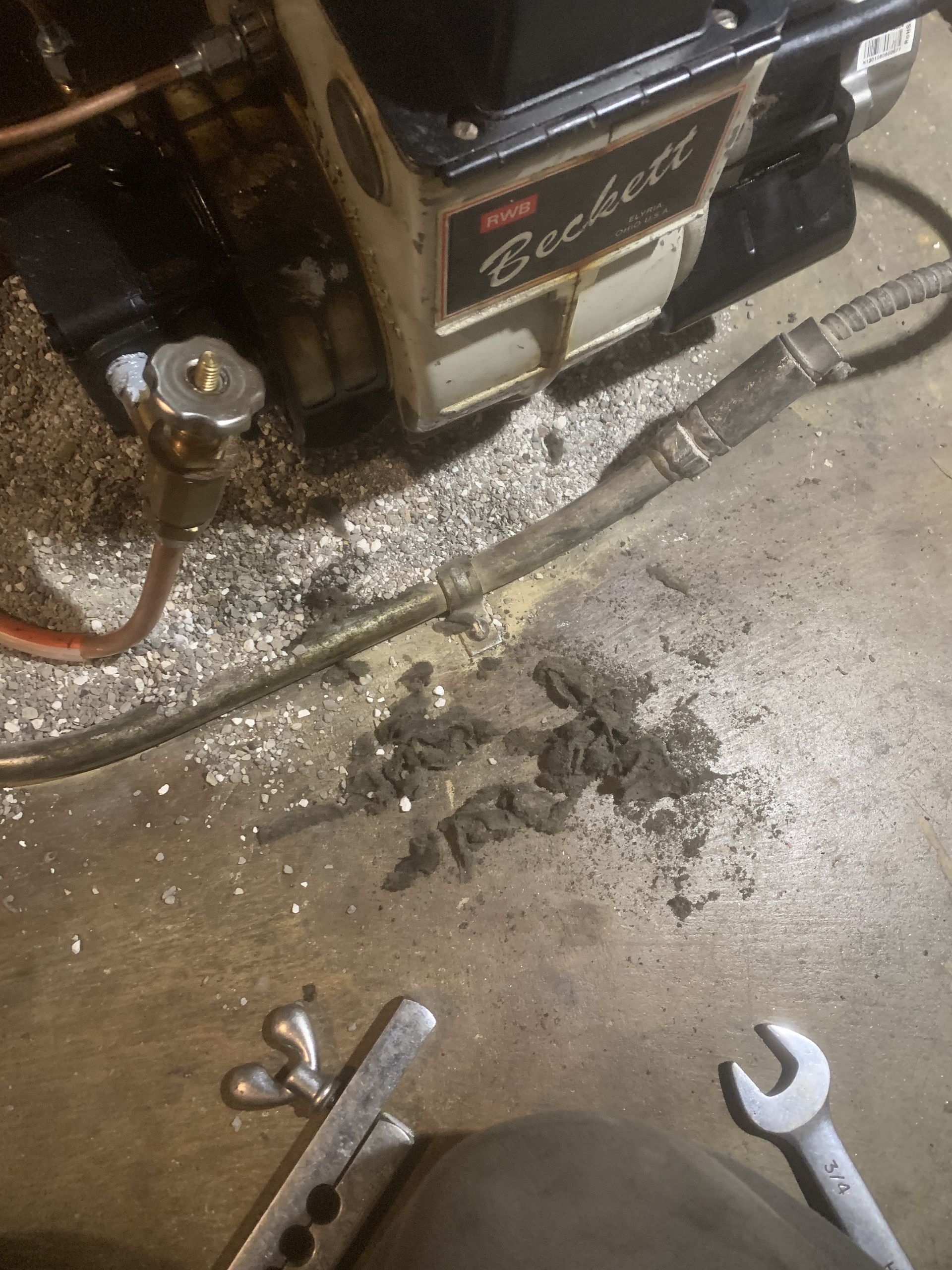A wrench is laying on the floor next to a machine.